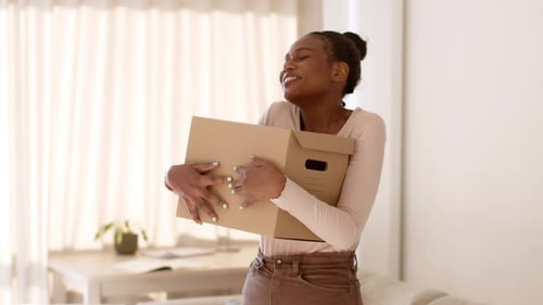 Woman Embraces Cardboard Box with Joyful Expression