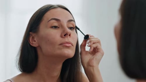 Confident Woman Applying Mascara at Mirror Place. Close Up Focused Lady Looking