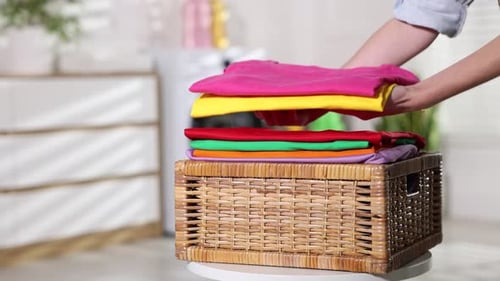 Freshly Laundered Clothes Being Stacked in Wicker Basket