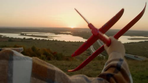 Child Holds Airplane Toy at Sunset Overlook