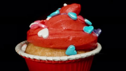 Festive Cupcake Topped with Hearts Against Black Background