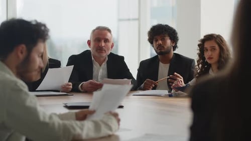Businessmen Review Charts and Financial Reports of the Company During a Meeting in the Office