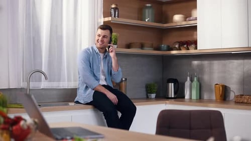 Young Man Talking on Phone in Bright Kitchen