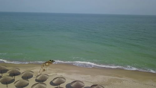 Aerial View of Straw Umbrellas on the Beach Ocean Waves Washing Sandy Shore Tranquil Coast Line of a