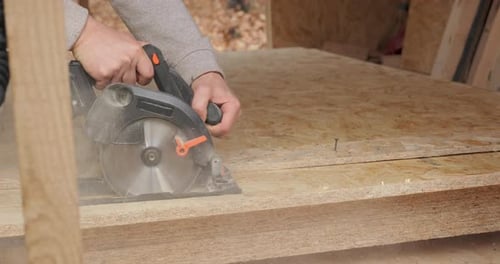 Gros plan d'un travailleur utilisant une scie circulaire pour couper du contreplaqué