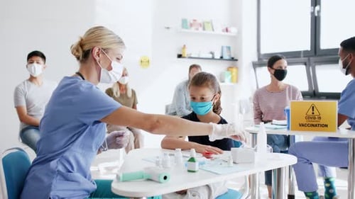 Child receives vaccination at medical clinic with other patients
