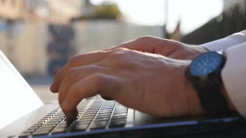 Close Up to Male Hands of Young Manager Typing Text on Notebook Keyboard Outdoor