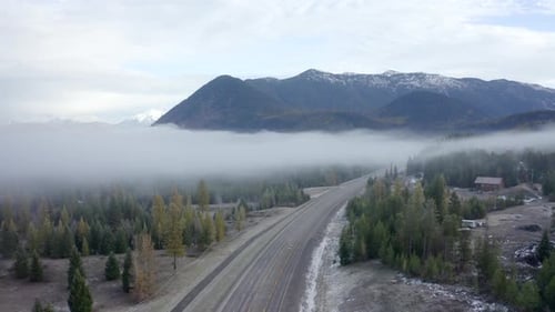Drone Shot Rising Above an Empty Road in a Foggy Valley with the Mountains of Montana in the Backgro
