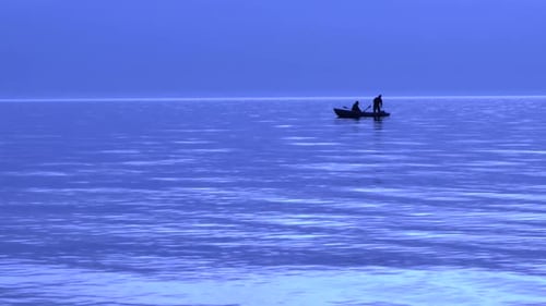 Baltic coast and purple sunset, two fishermen on boat, slow motion