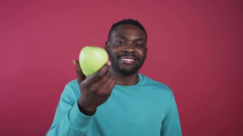 Smiling Young Adult Holding a Green Apple
