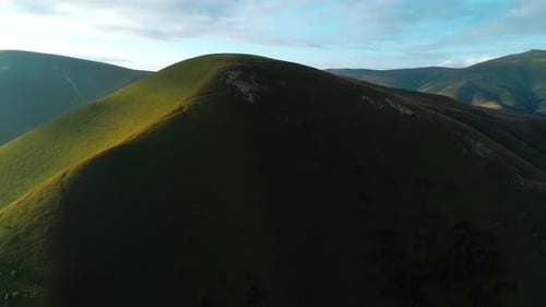 Nahaufnahme von Hügeln, die mit grünem Gras bedeckt sind und auf der anderen Seite Sonnenlicht und auf der anderen Seite Schatten