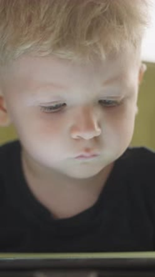 Focused Blond Child Uses Digital Tablet