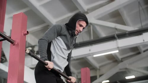 Young Athlete Wearing Hood Exercising on Pushup Bar at Gym