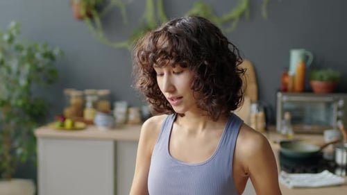 Young Woman Drinks Healthy Smoothie in Kitchen