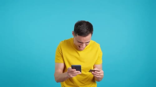 Homme faisant des achats compulsifs avec une carte de crédit et un téléphone portable