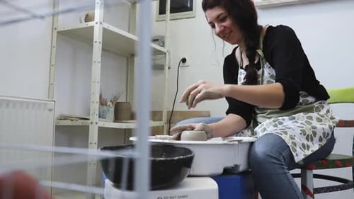 Young artist in the pottery studio making bowl with her hands, handmade creative artist