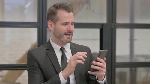 Man in Suit Celebrates Using Smartphone