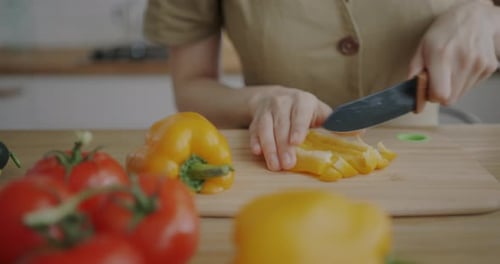 Woman Chopping Yellow Pepper in a Kitchen