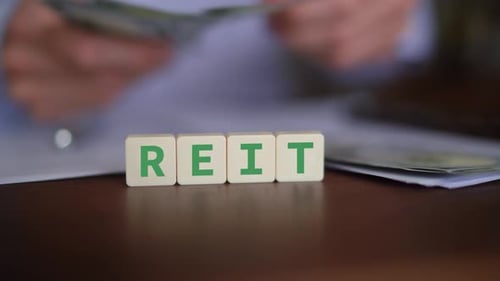 Concept of investing in Real Estate Investment Trust. REIT initials with selective focus and money o
