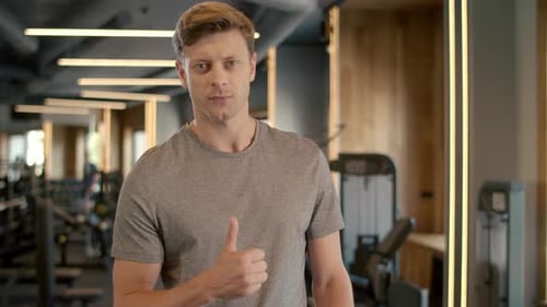 Portrait of Serious Fitness Man Showing Thumb Up Sign at Gym. Confident