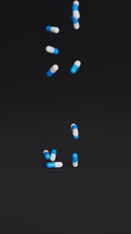 White and Blue Pills Falling on Black Background in Slow Motion Drugs Pills Tablets Medicine Concept