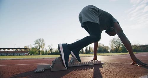 Zeitlupe eines jungen afrikanischen männlichen Athleten startet bei einem Leichtathletikrennen von der Startlinie