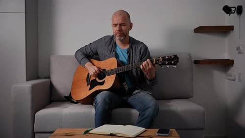 Adult Plays Guitar in Modern Living Room