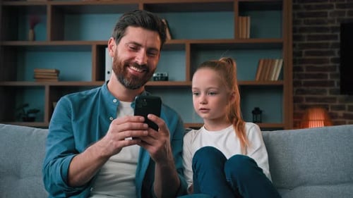Father and Daughter with Smartphone on Couch