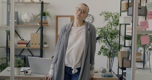 Successful Young Lady Standing in Modern Office with Glass Walls Smiling Looking at Camera