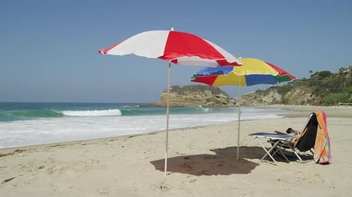 Folding Chair And Colorful Umbrellas At Empty Beach On A Sunny Summer Day. - wide shot