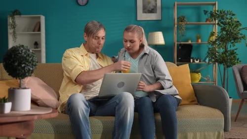 Happy Couple Relaxing at Home with a Laptop