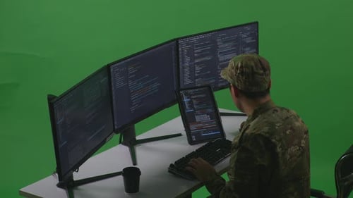 Side View Of Man Soldier Working With Tablet While Write Code With Multiple Screens In Green Screen