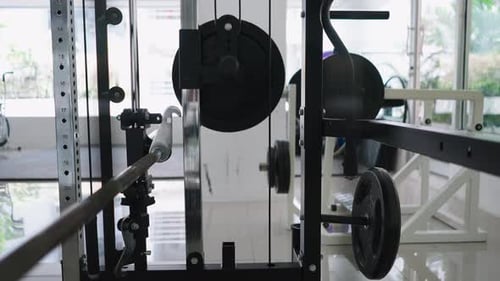 Closeup View of Gym Equipment Next to Weights and Swivel Cables in a Brightly Lit Gym