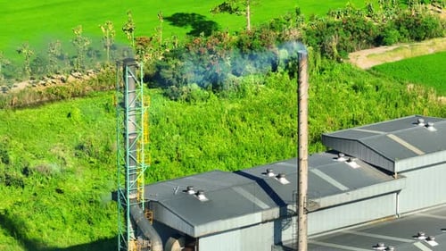Factory With Smokestacks Emitting Smoke in Rural Setting