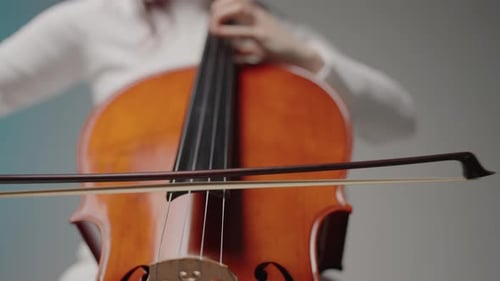 Beautiful Woman Sitting and Playing the Cello in a Studio on a White Background
