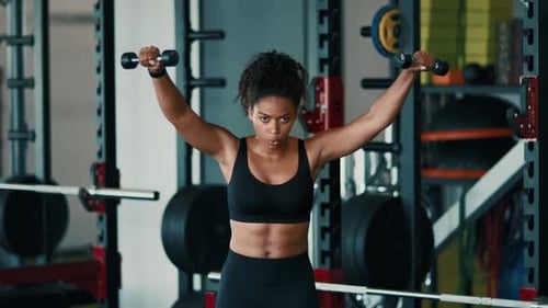 Woman Exercising With Weights in a Gym Setting During the Day
