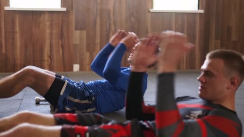 Des hommes athlétiques au gymnase faisant une série de situps actifs en forme de combattants masculins en tenue de sport