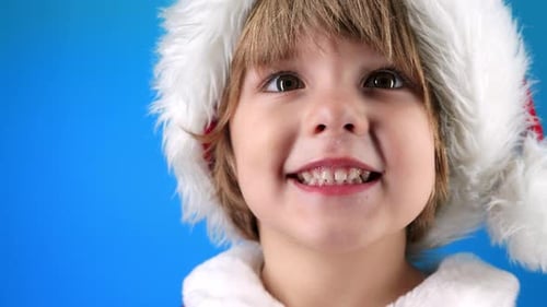 Portrait of Adorable Boy in Santa Claus Hat on Blue Studio Background