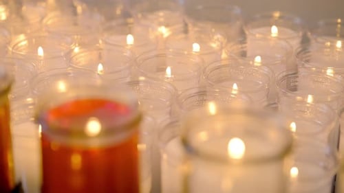 Sanfte, warme Aufnahme vieler kleiner Gedenkkerzen, die eng angeordnet sind und die flackernden Flammen glühen lassen