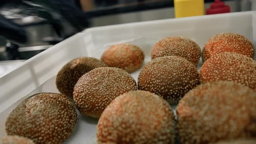 Burger buns are stacked in a food container in a restaurant kitchen