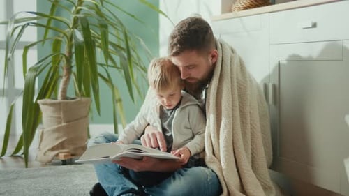 Father and Child Reading a Book Indoors