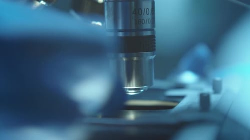 Hand of Scientist Placing Glass Slide with Specimen on Microscope Stage