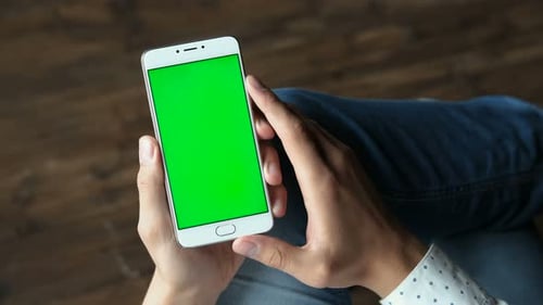 Man holds greenscreen cellphone scrolling and tapping in airport lounge