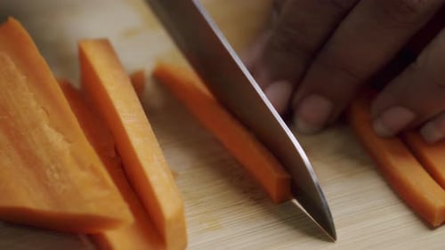 Chopping Fresh Orange Carrots on Cutting Board