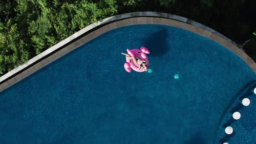 Mulher turista nadando com flamingo rosa inflável na piscina infinita