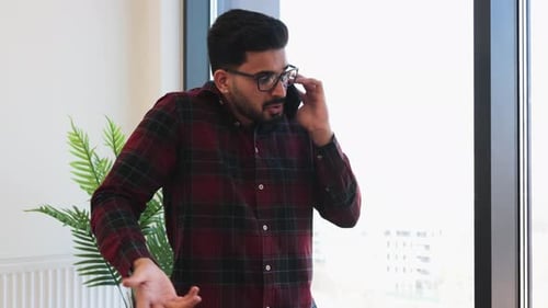 Young Man Talking on Phone in Modern Office Setting
