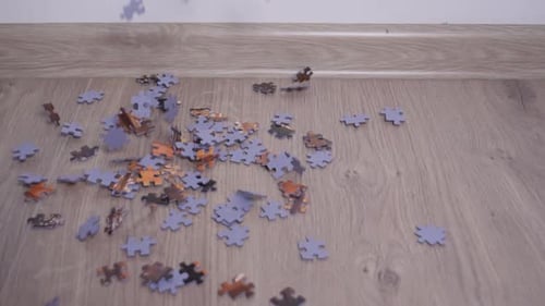 Jigsaw puzzle pieces fall down in slow motion on ground, close up.