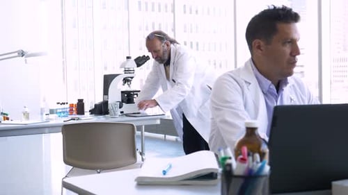 Senior hispanic scientist uses microscope for research in science laboratory