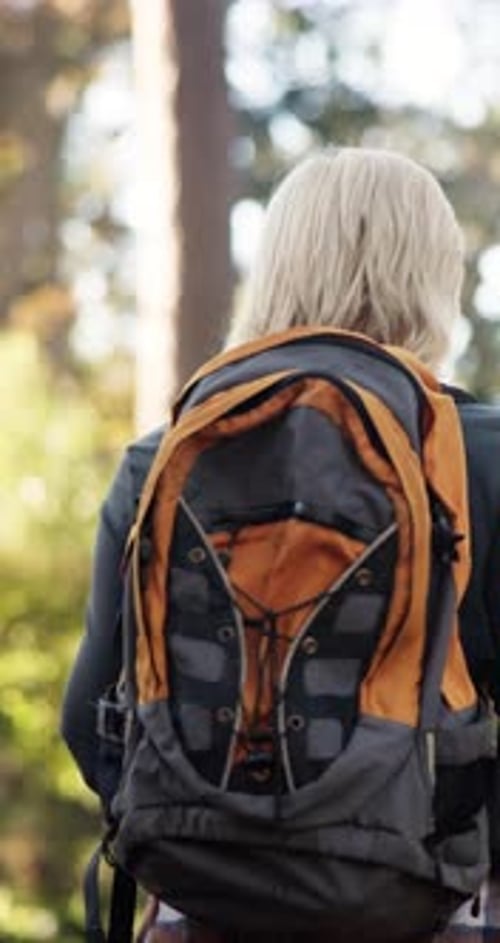 Hiking, backpack and woman walk in woods for travel, sightseeing or thinking in retirement