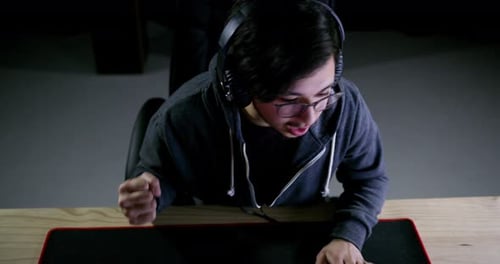 Excited Gamer Playing Online with Headset and Keyboard